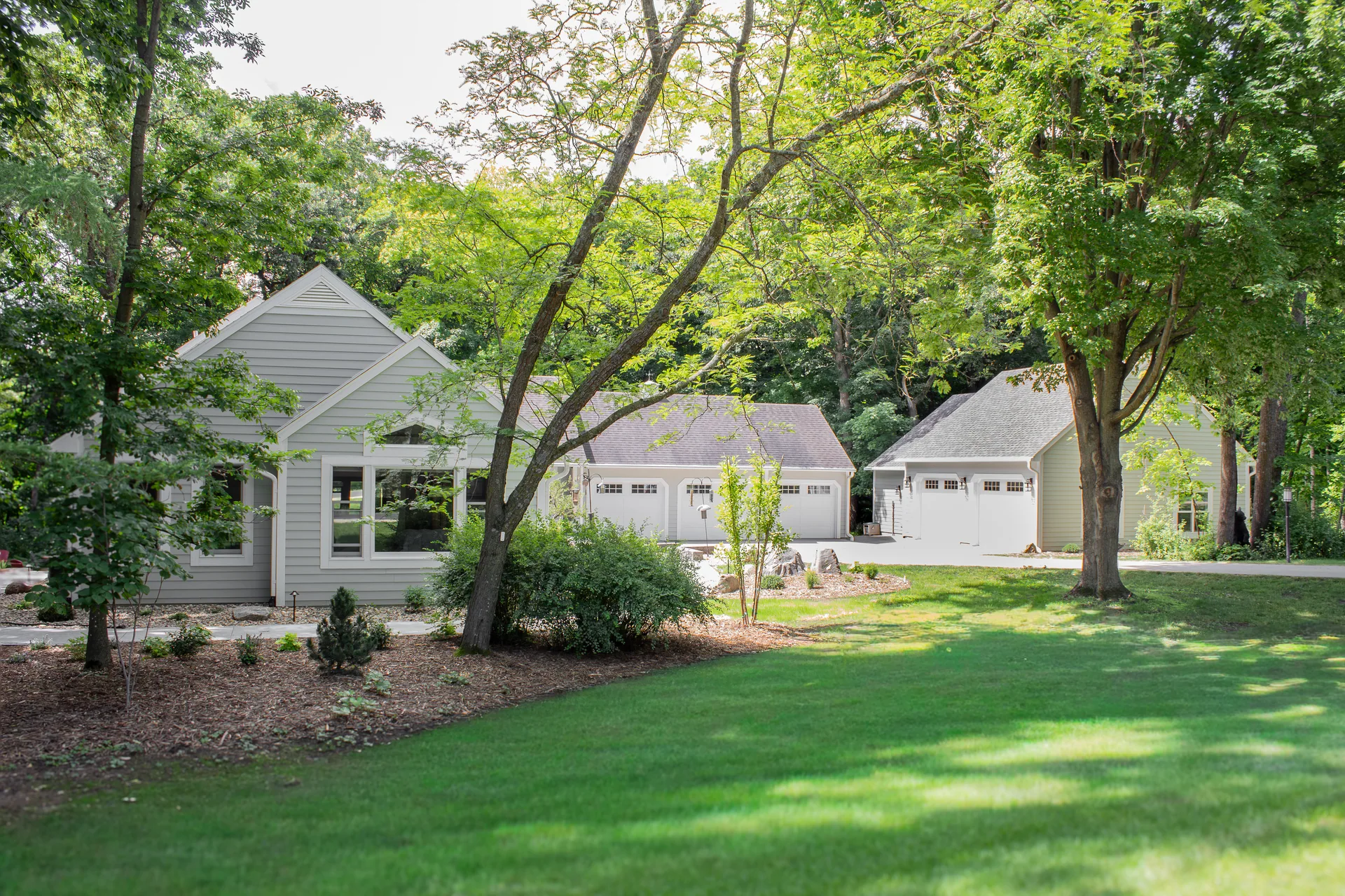Home addition and detached garage set among mature trees