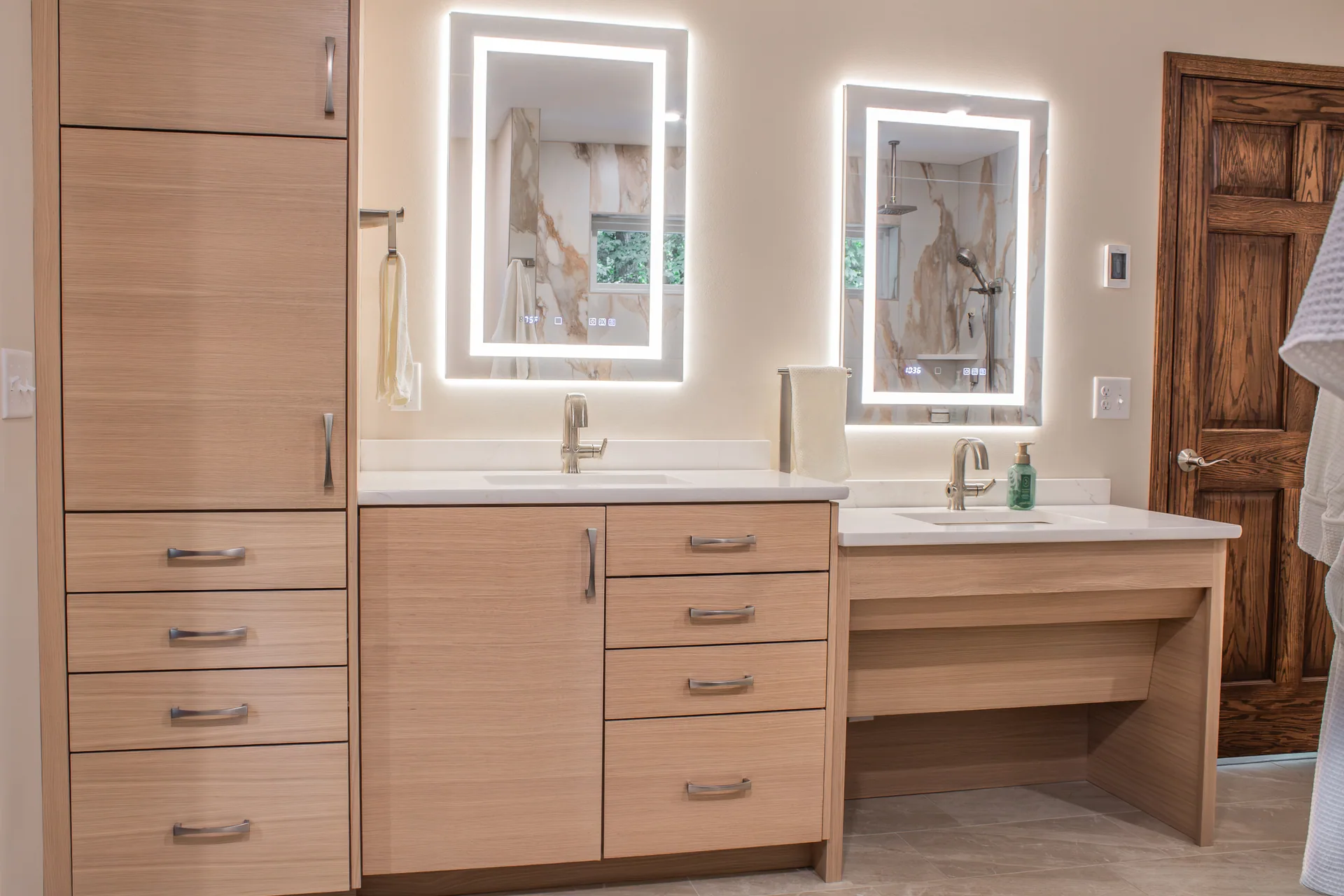 Primary bathroom cabinetry with illuminated mirrors