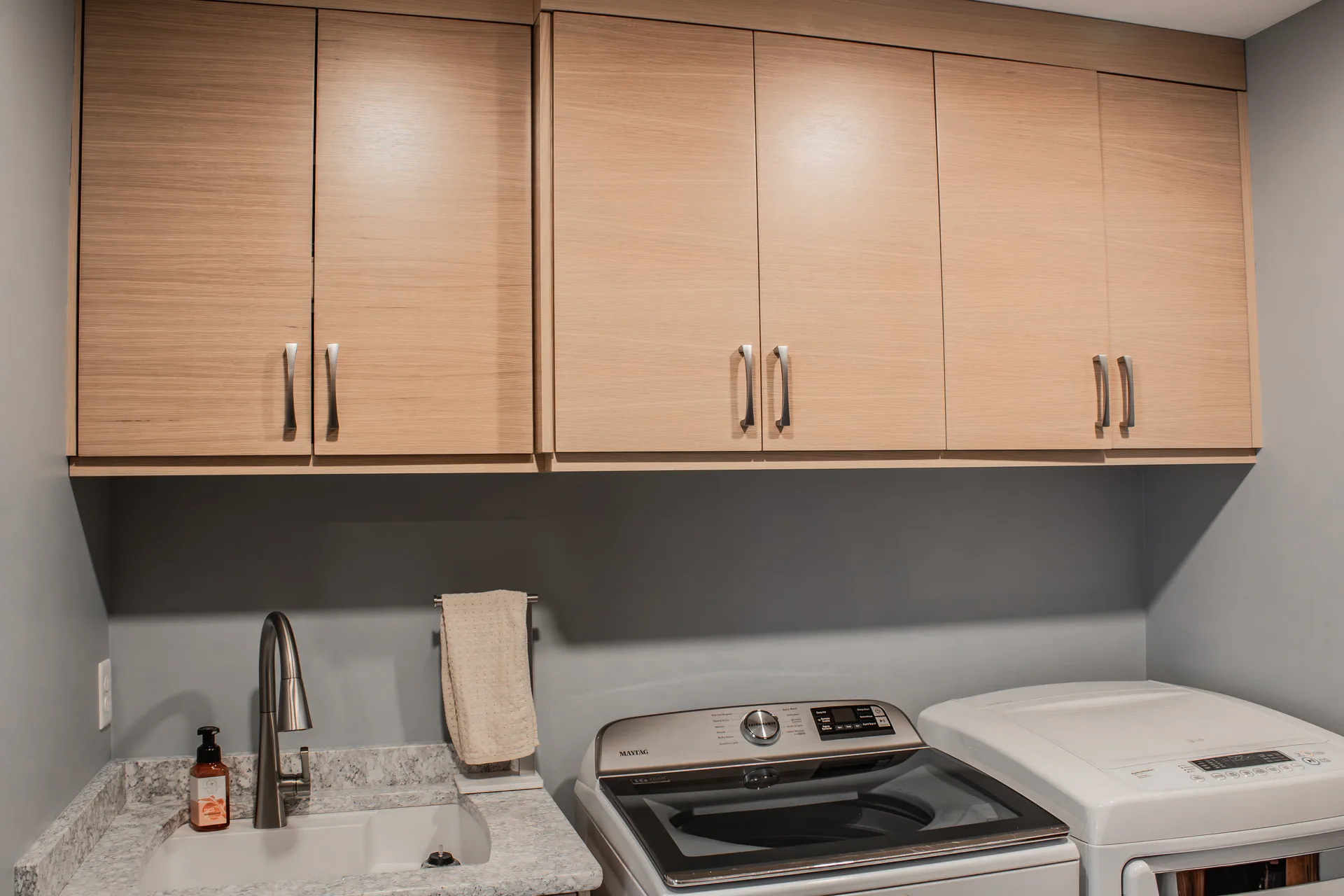 Wood laundry cabinets above washer and dryer